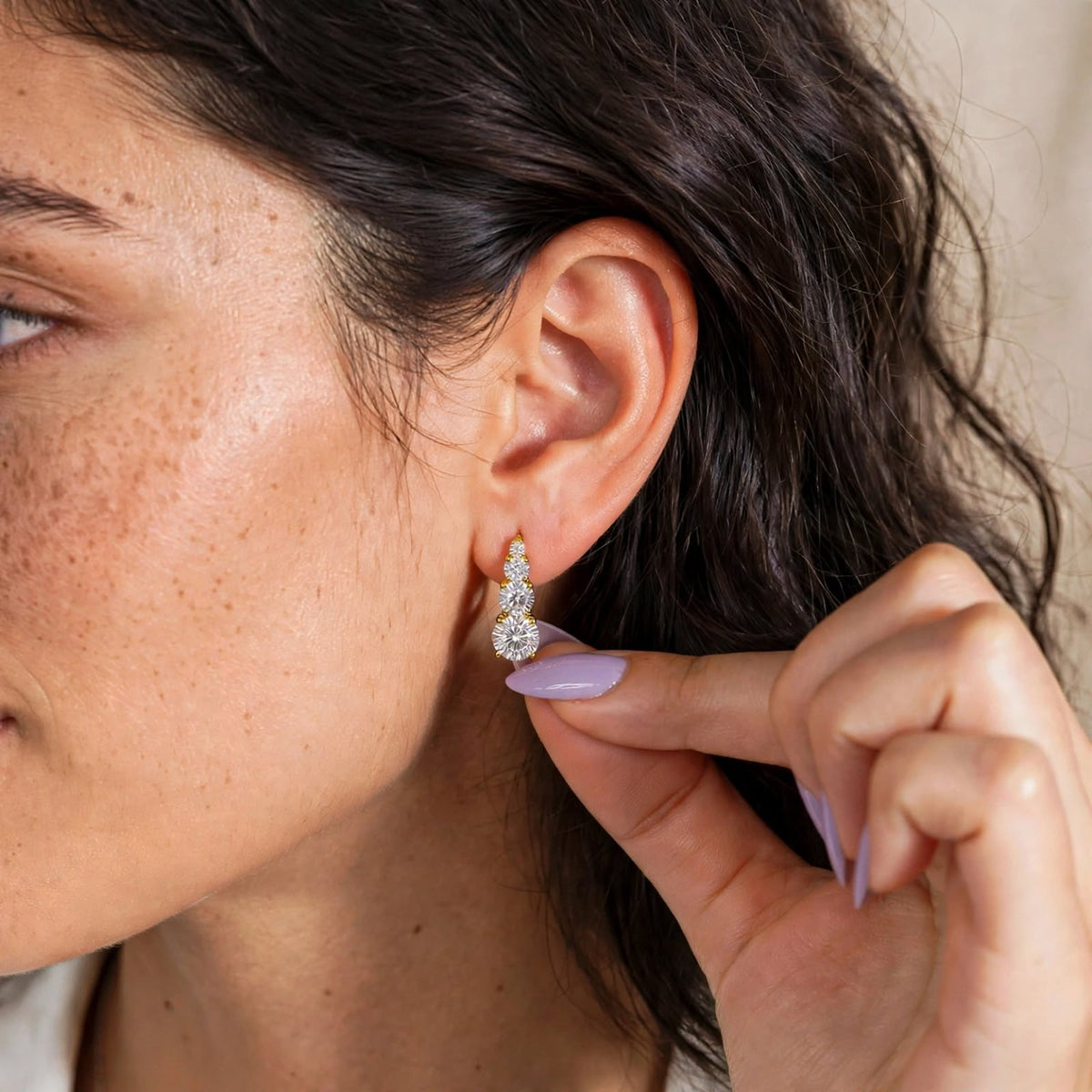 Gold graduated moissanite hoop earring worn on ear