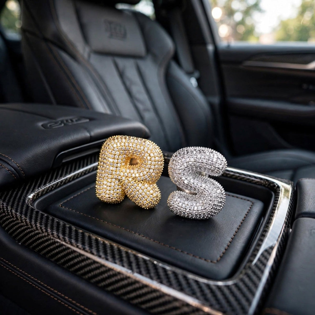 The Campbell Soup gold R and silver S rings on luxury black leather car console