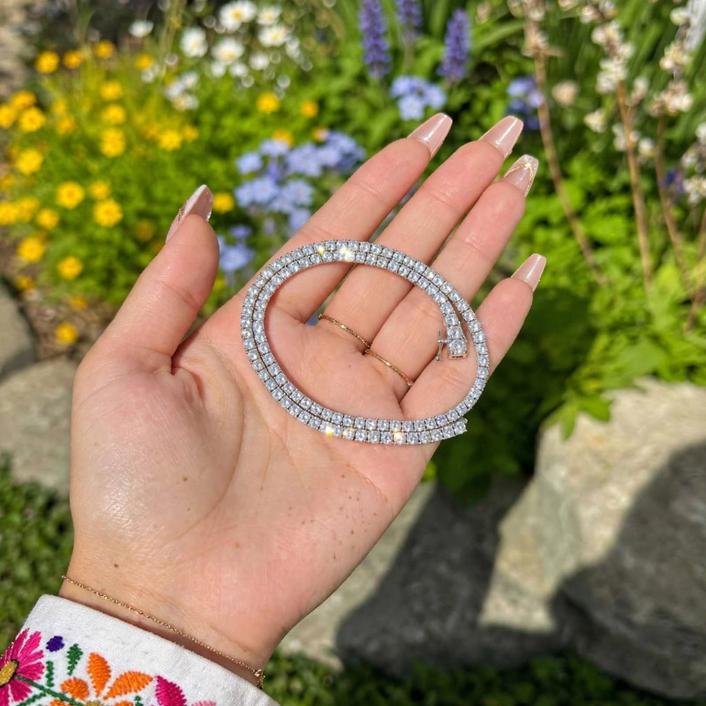 Silver tennis necklace shown in hand outdoors