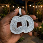 The Full Court Pressure custom baguette iced pendant held outdoors beneath warm string lights