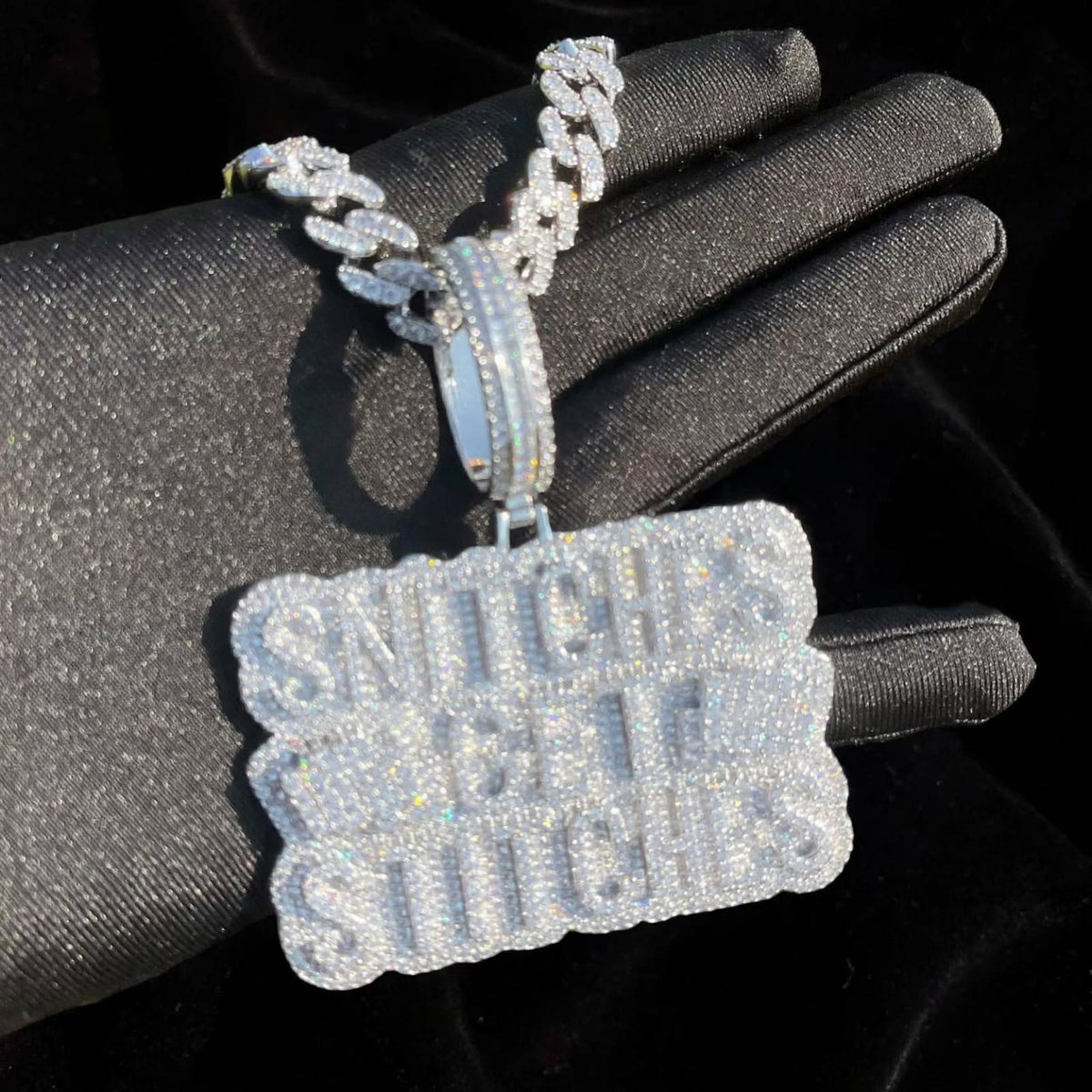 Silver iced-out stacked-letter pendant on black glove