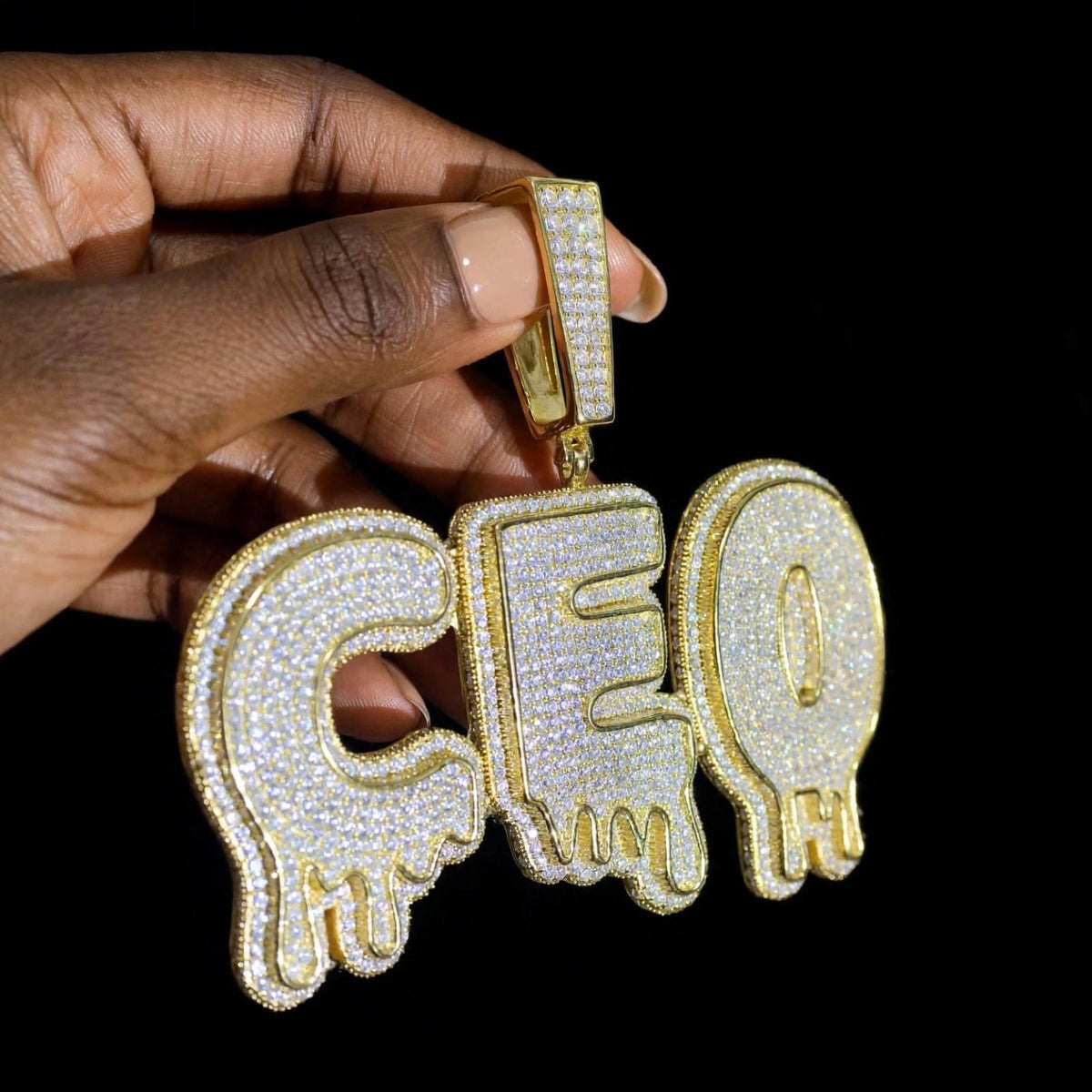 The Drip gold CEO pendant, angled side view showing iced bail and lettering