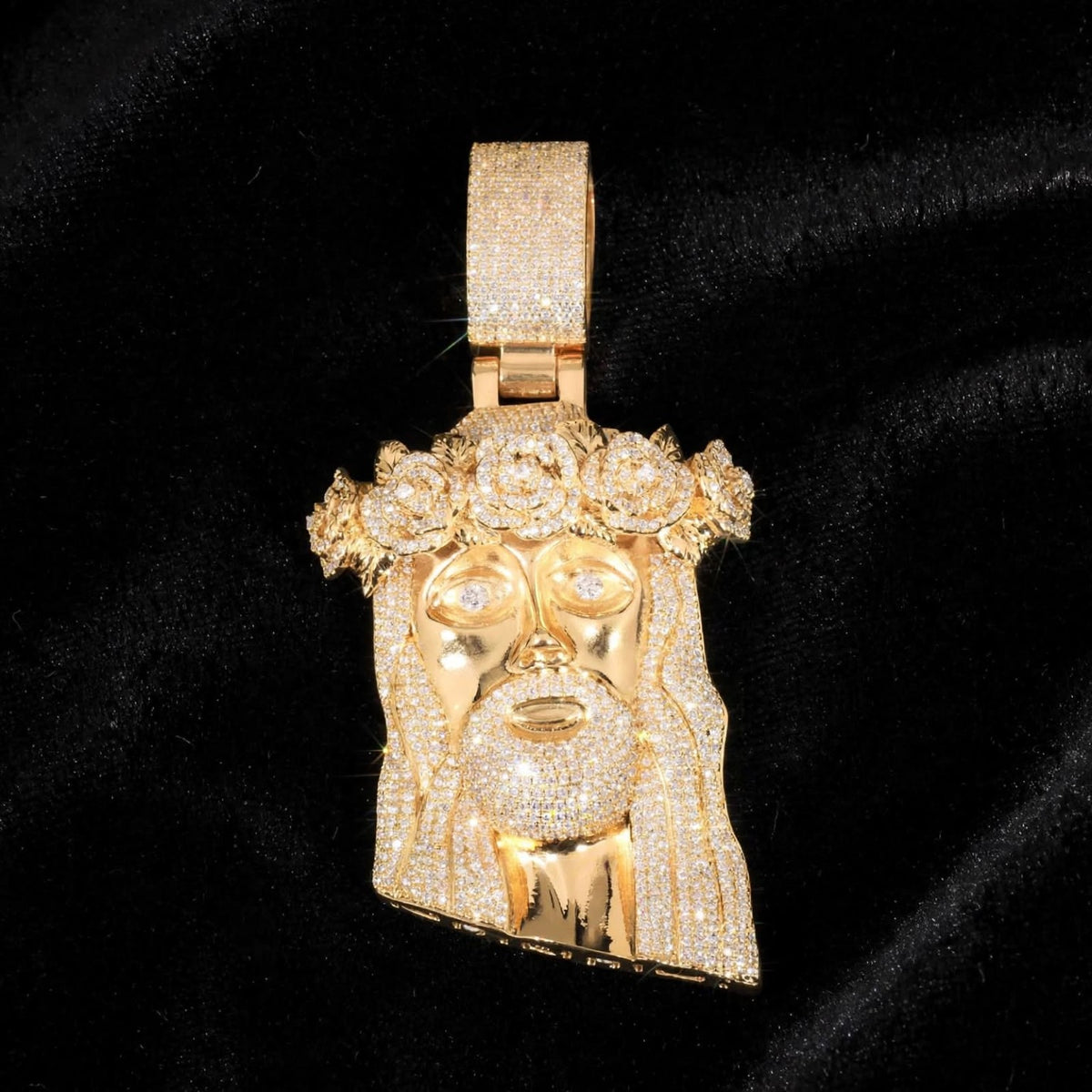 Gold Jesus pendant and iced rose crown against black velvet