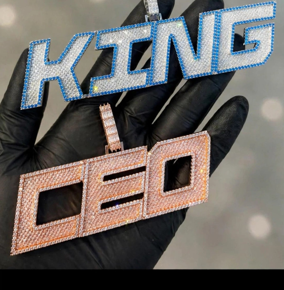 KING blue-accent custom pendant and rose-color DEO pendant held in black glove