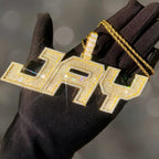 Gold-color JERRY iced-out custom block-letter pendant displayed on a black glove