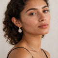 Model in black dress wearing gold-tone pear-cut moissanite halo drop earring