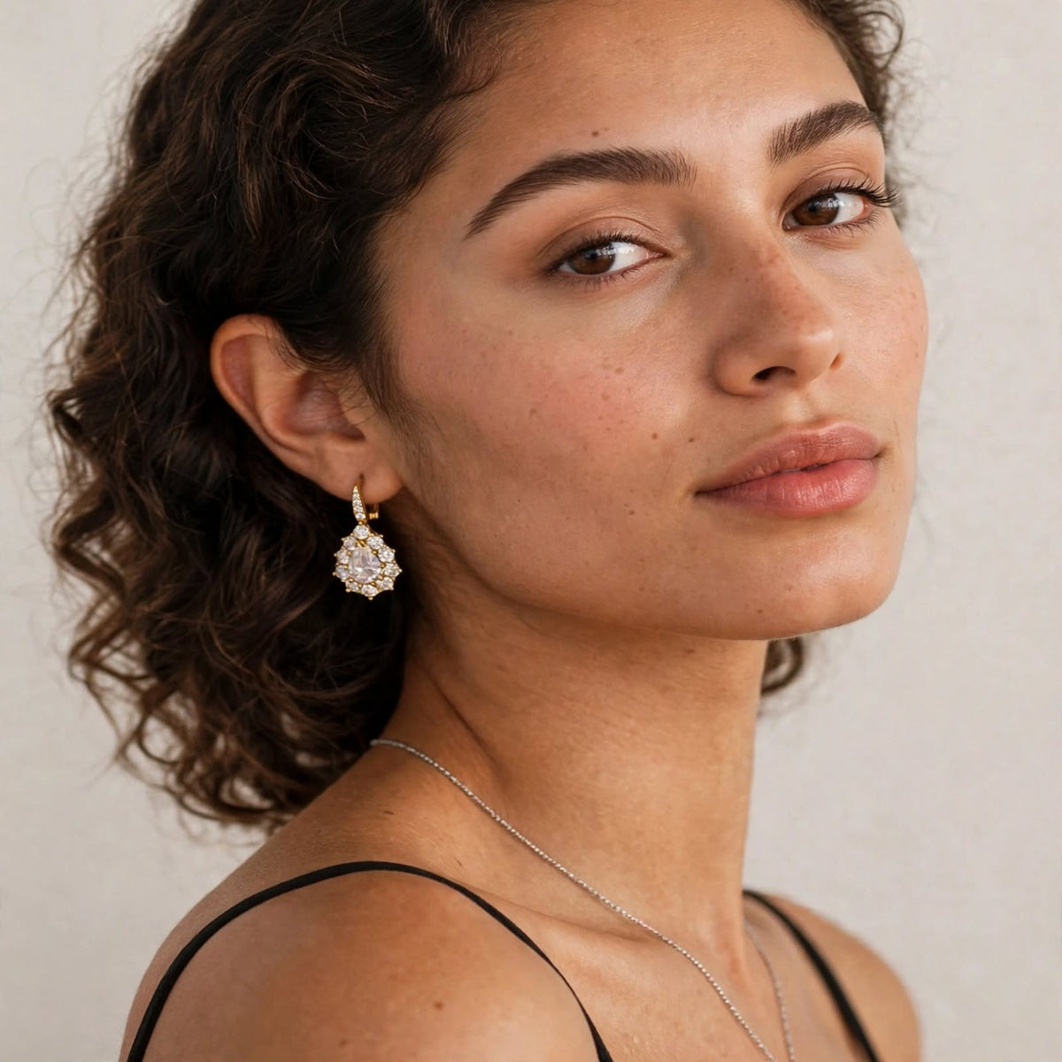 Model in black dress wearing gold-tone pear-cut moissanite halo drop earring