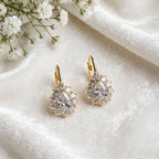 Gold-tone pear-cut halo drop earrings on white satin fabric