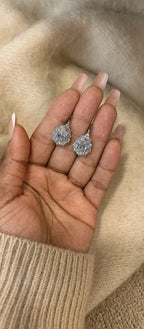 Silver-tone pear-cut moissanite drop earrings displayed on hand