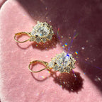 Pair of gold-tone pear-cut moissanite halo earrings on rose velvet
