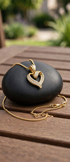 The Golden Embrace open-heart gold-tone necklace resting on black stone