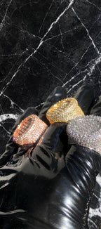 The Introduction fully iced-out statement rings in Gold, Rose Gold, and Silver on black latex gloves
