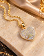Gold-tone iced heart necklace resting on marble stone