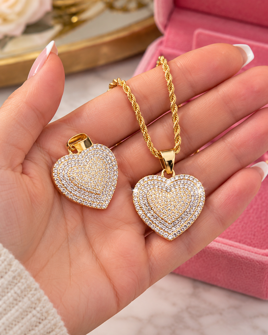 Gold-tone iced heart necklace displayed on a woman's hand